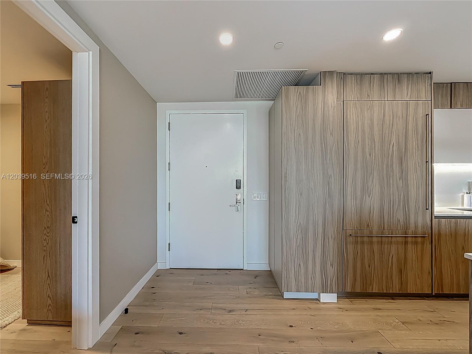 An entryway features light wood flooring, a white door, and integrated wood-paneled cabinetry — 350 Ocean Dr # 305N, Key Biscayne FL 33149, KEY BISCAYNE, FL