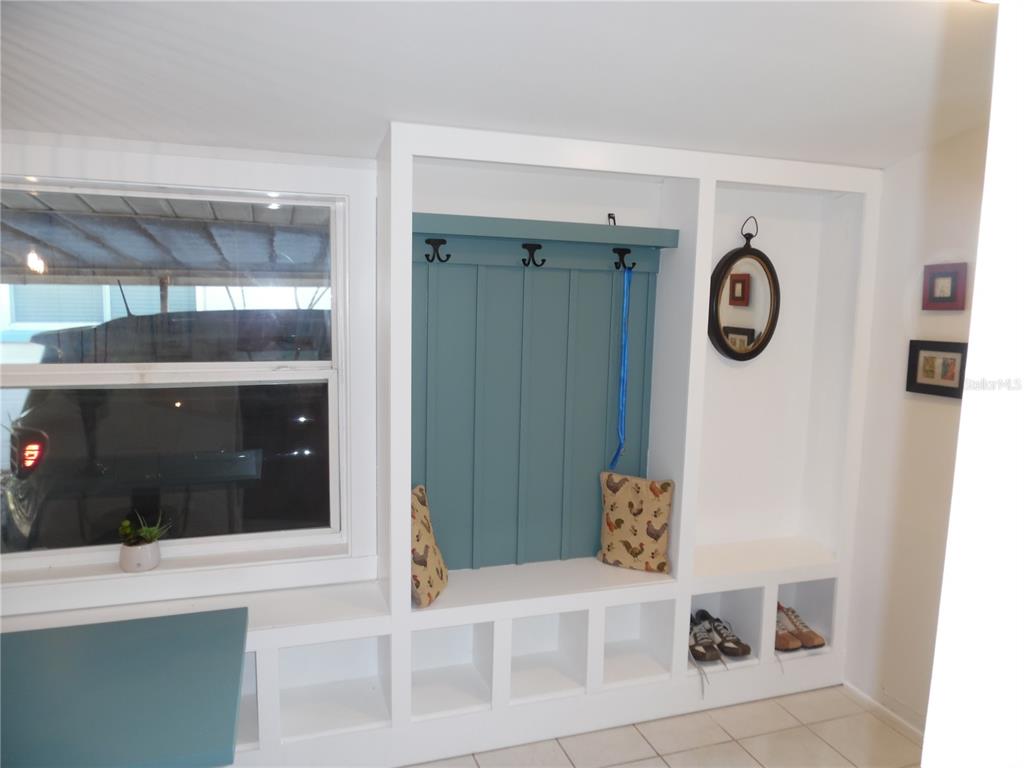 A white built-in mudroom bench with a blue paneled back, coat hooks, and cubby storage — 5487 70TH WAY N, ST PETERSBURG, FL