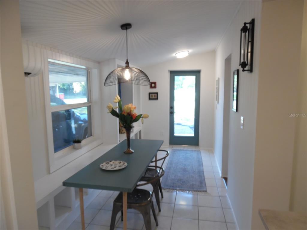 A dining area features a long table, metal chairs, a pendant light, and tile flooring — 5487 70TH WAY N, ST PETERSBURG, FL