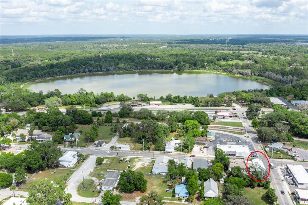 An aerial view shows a small commercial building circled in red near a lake — 6880 SE 221ST STREET, HAWTHORNE, FL