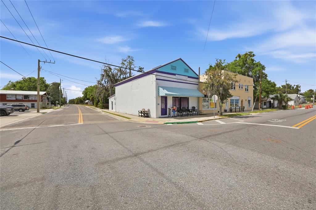 A street corner view shows a white building with a blue roof and awning — 6880 SE 221ST STREET, HAWTHORNE, FL