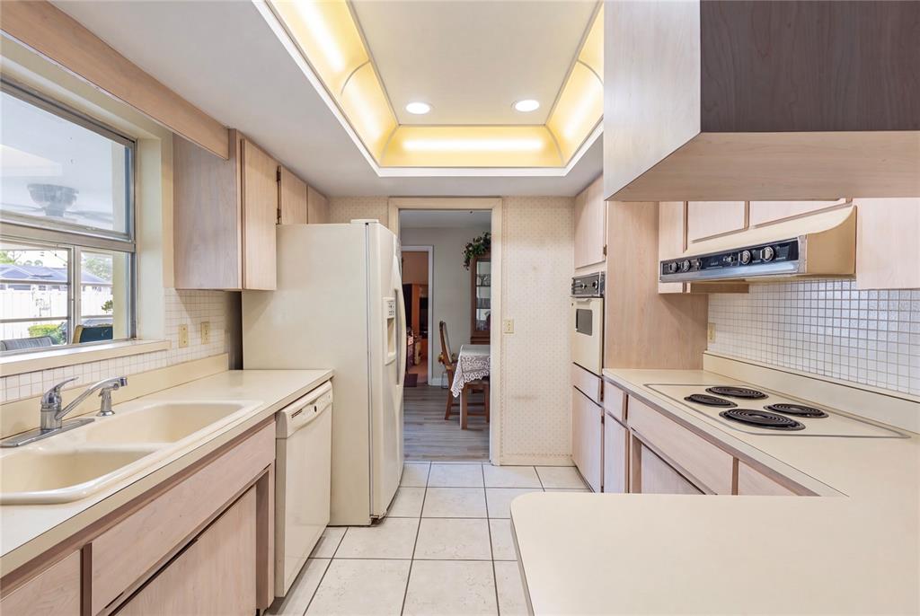 A kitchen with light wood cabinets, white appliances, tile flooring, and a recessed ceiling light — 1081 MCFARLAND STREET, DUNEDIN, FL