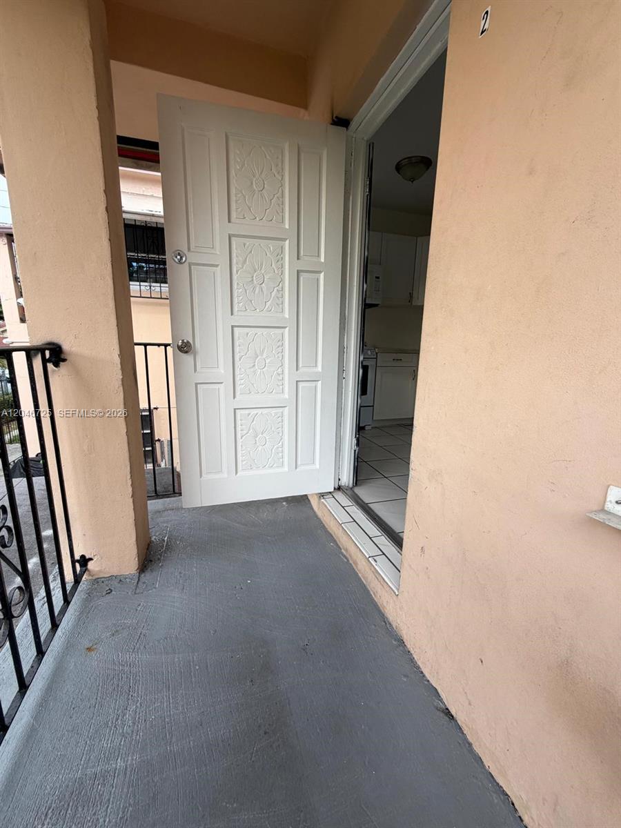 An open white door leads from a gray-painted balcony into a kitchen with tiled floors — 1036 NW 3rd St # 2, Miami FL 33128, MIAMI, FL