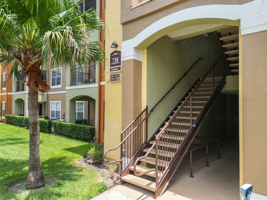 An exterior view of a multi-story apartment building with a staircase leading to upper units — 738 CREST PINES DRIVE UNIT 726, ORLANDO, FL