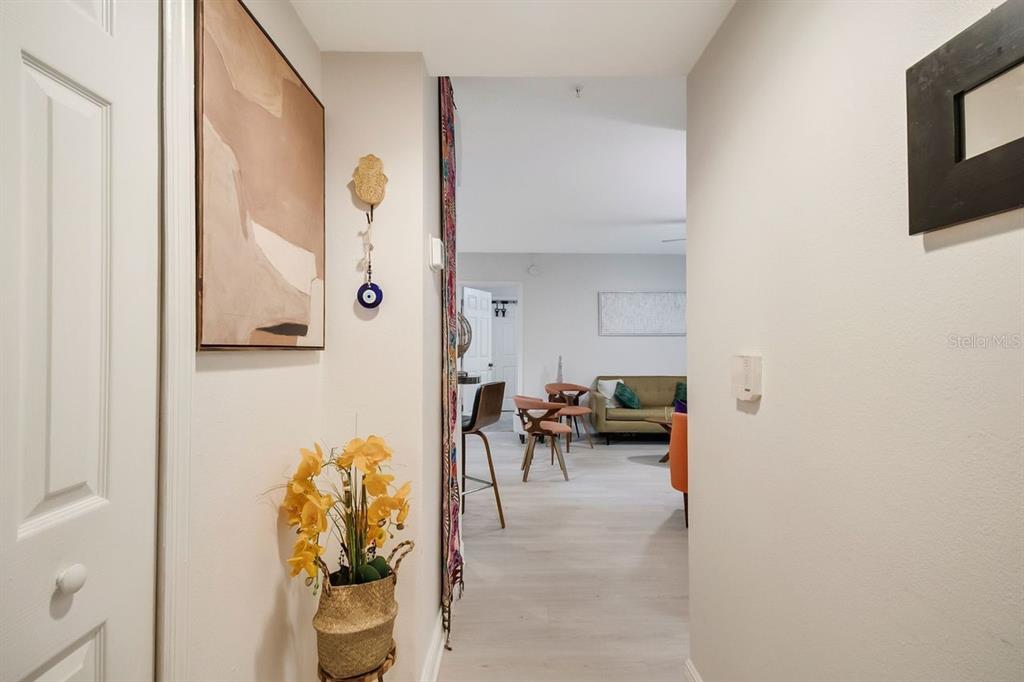 A hallway with light wood flooring leads into a living area with a sofa — 738 CREST PINES DRIVE UNIT 726, ORLANDO, FL
