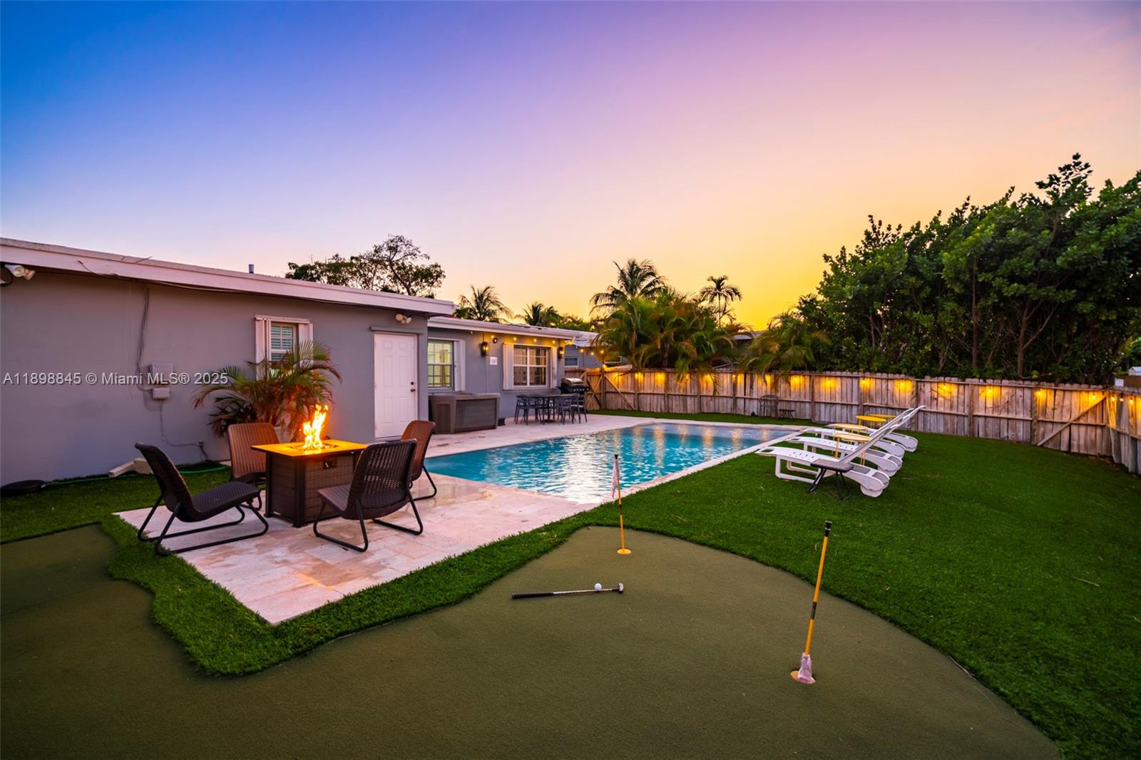 A backyard features a swimming pool, a putting green, a fire pit, and lounge chairs — 1305 Funston St, Hollywood FL 33019, HOLLYWOOD, FL