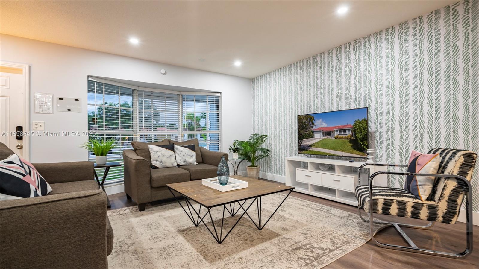 A living room features a patterned accent wall, a television, and modern furniture — 1305 Funston St, Hollywood FL 33019, HOLLYWOOD, FL