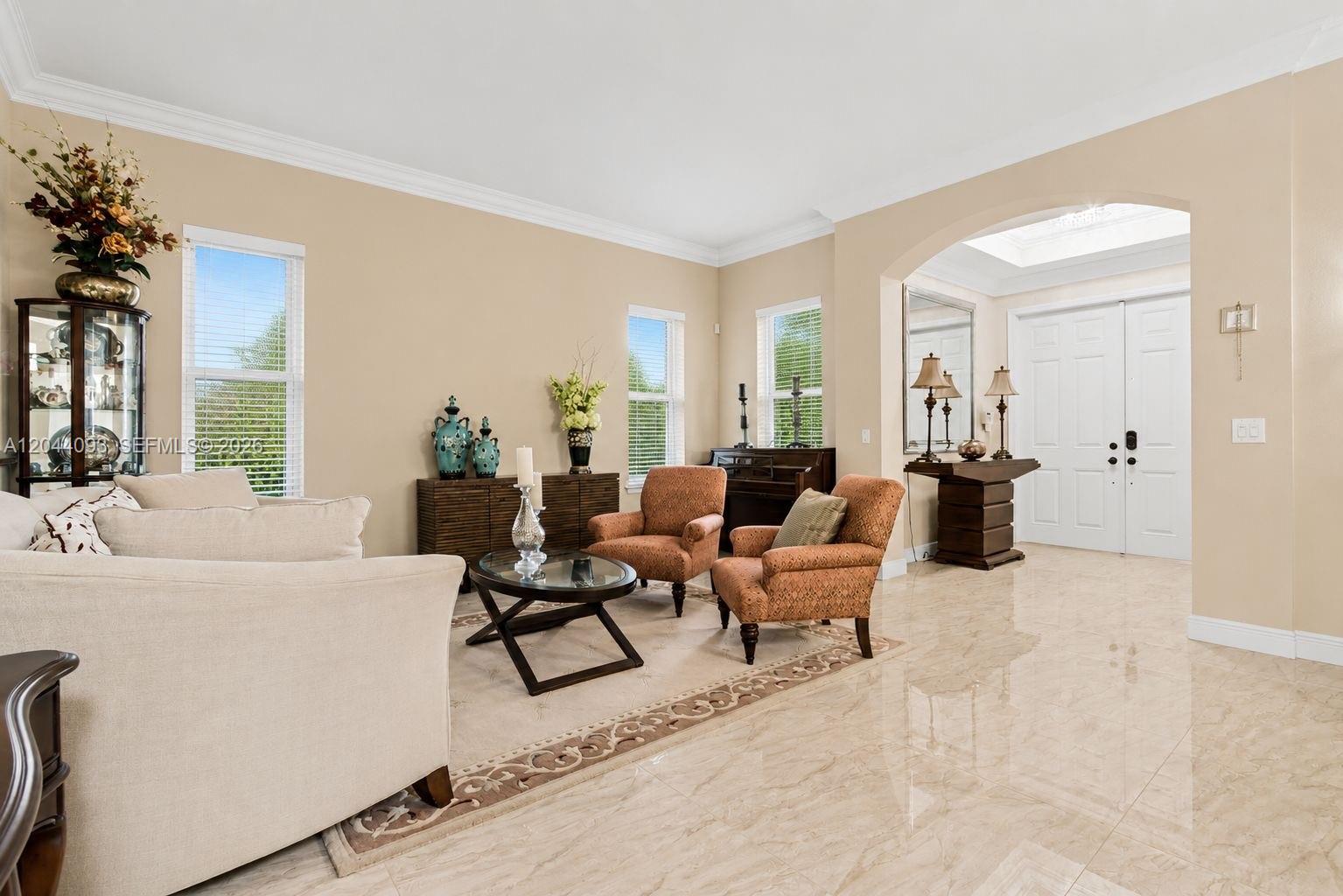 A living room features beige walls, tile flooring, two armchairs, and an arched entryway — 4200 Key Lime Blvd, Boynton Beach FL 33436, BOYNTON BEACH, FL