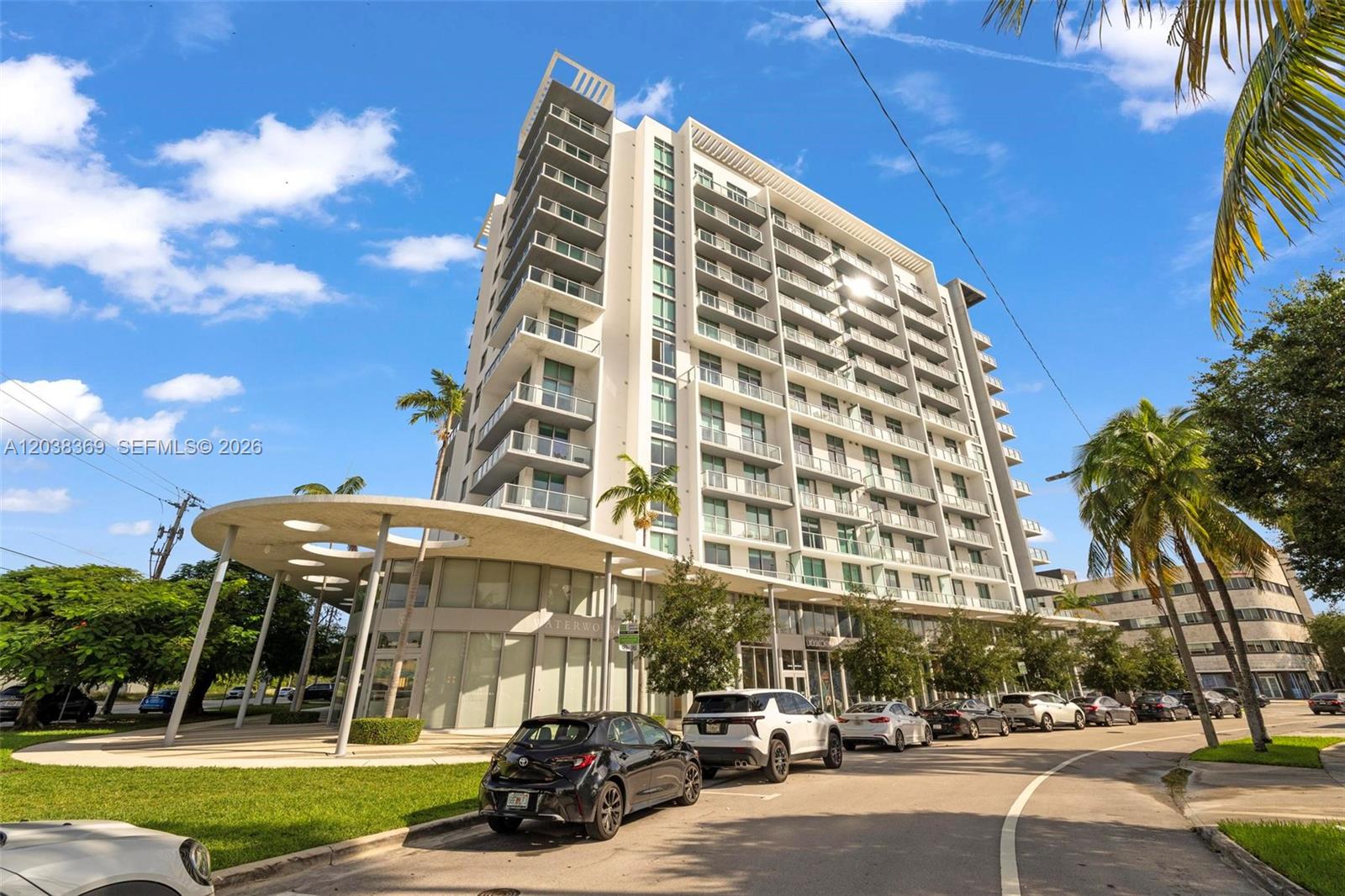 A modern multi-story residential building features glass balconies and a circular covered entrance canopy — 3900 Biscayne Blvd # 418, Miami FL 33137, MIAMI, FL