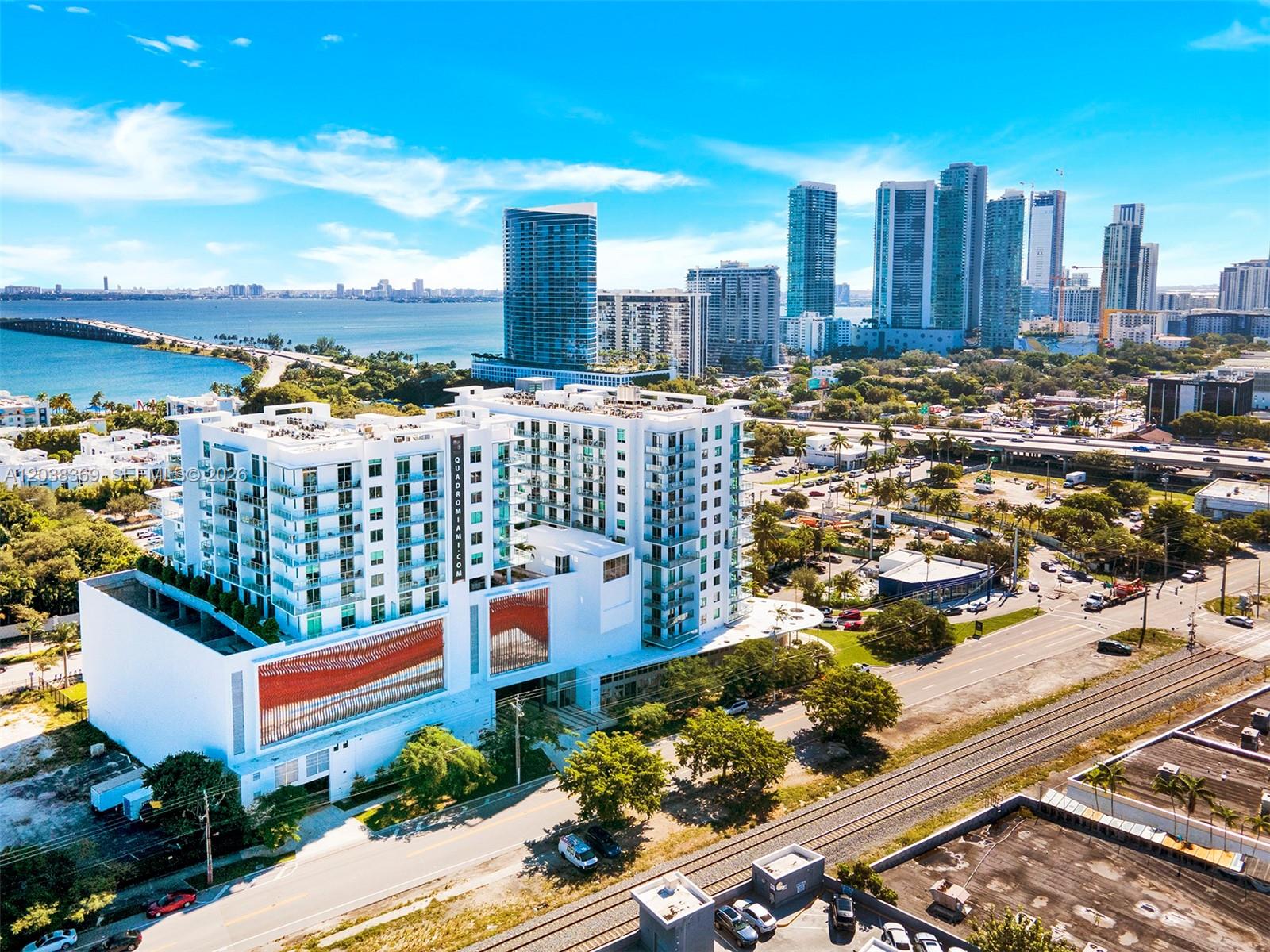 An aerial view of a white modern apartment building next to railroad tracks in Miami — 3900 Biscayne Blvd # 418, Miami FL 33137, MIAMI, FL