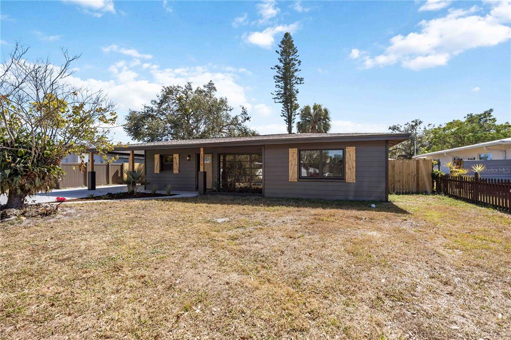 A single-story house with dark gray horizontal siding and wood-accented window shutters — 2770 WOOD STREET, SARASOTA, FL