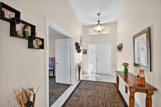 A bright entryway features a tiled floor, a wooden console table, and a modern light fixture — 10299 Utopia Circle W, Boynton Beach FL 33437, BOYNTON BEACH, FL