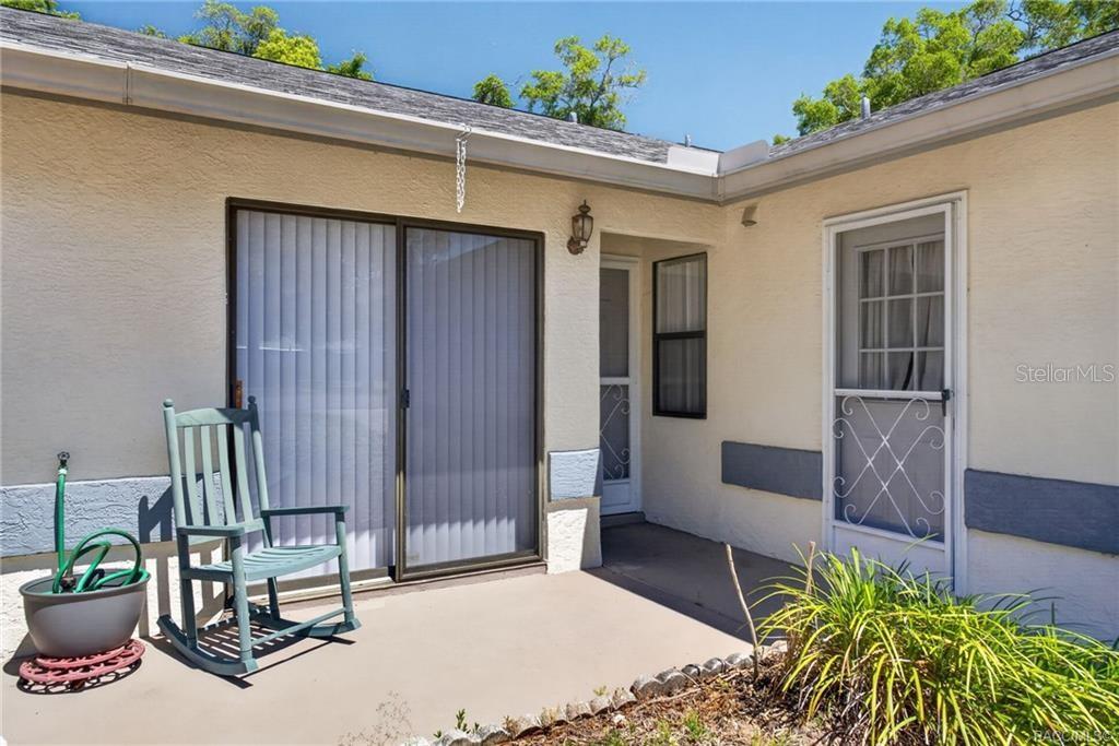A patio area features a sliding glass door, a screen door, and a rocking chair — 1846 JUNEBERRY LANE, INVERNESS, FL