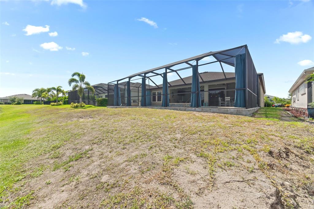 A screened-in patio features a swimming pool, a stone fire pit, and outdoor seating — 5416 LIMELIGHT DRIVE, APOLLO BEACH, FL