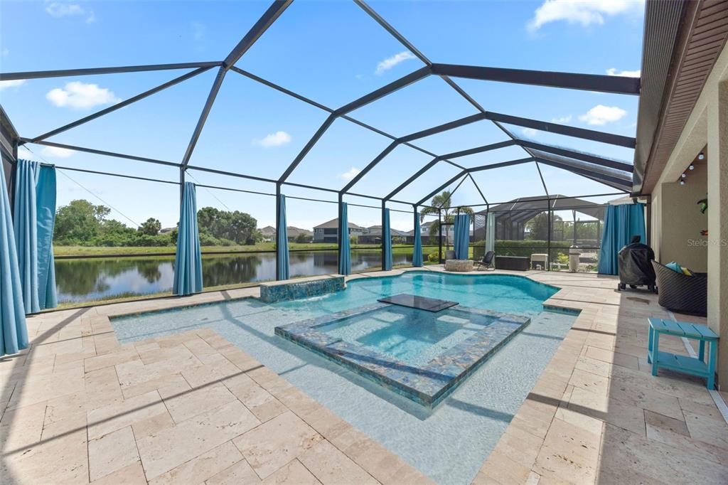 A screened-in pool and spa area with stone pavers overlooking a lake — 5416 LIMELIGHT DRIVE, APOLLO BEACH, FL