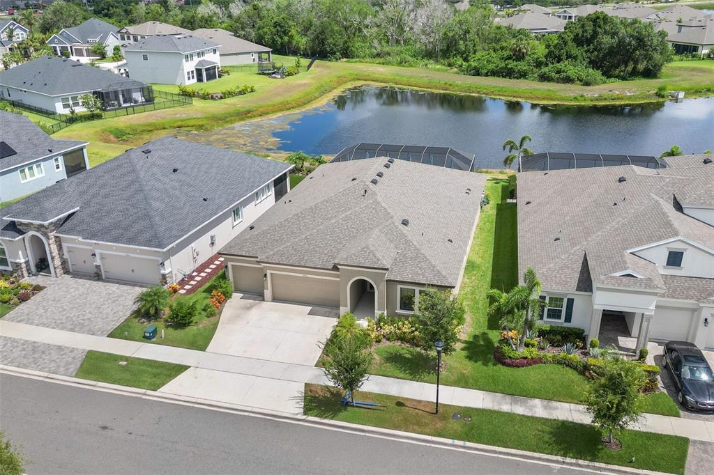 A screened-in pool area features a stone fire pit and views of a pond — 5416 LIMELIGHT DRIVE, APOLLO BEACH, FL