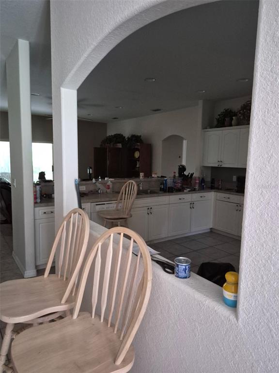 A kitchen with white cabinets and a breakfast bar viewed through an arched opening — 3163 FOREST CREEK DRIVE, MELBOURNE, FL