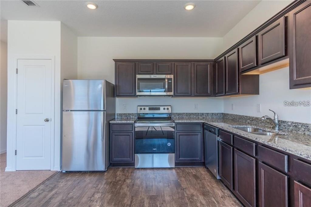 A kitchen featuring dark wood cabinets, stainless steel appliances, and granite countertops — 342 MADISON DRIVE, DAVENPORT, FL