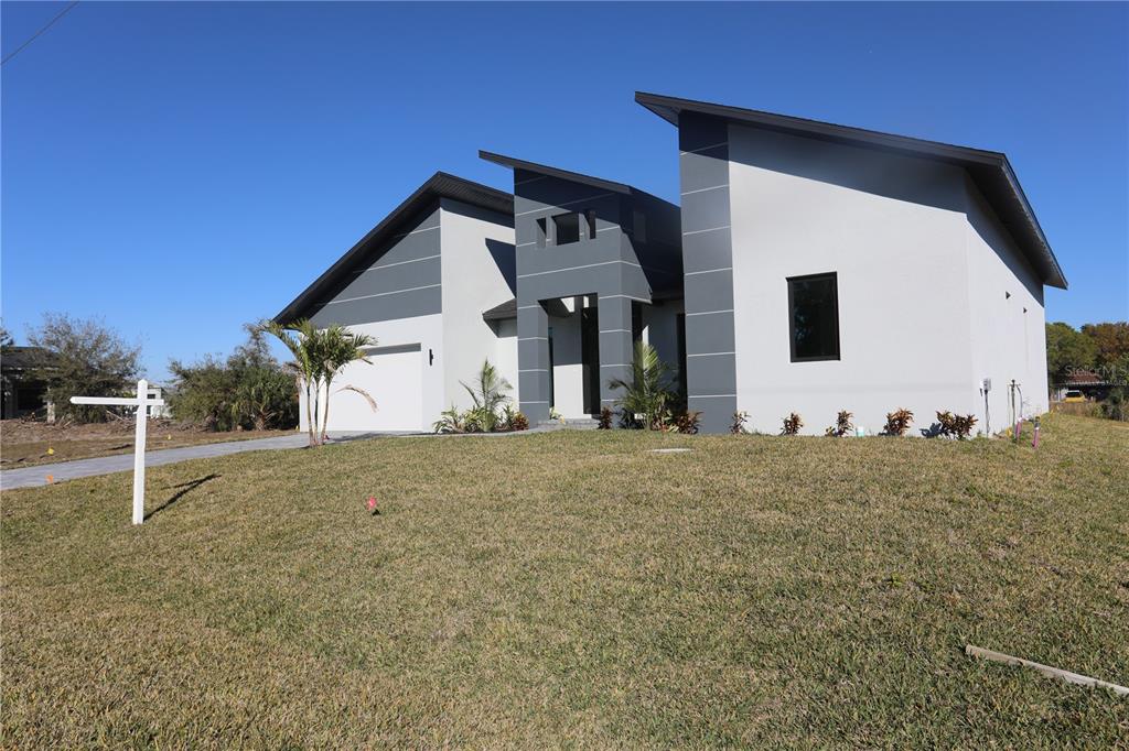 A modern, single-story house with a gray and white exterior and a slanted roofline — 9574 SALT LAKE STREET, PORT CHARLOTTE, FL
