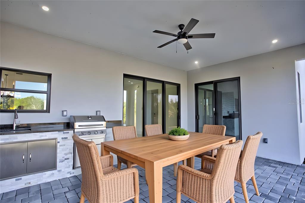 A covered outdoor patio features a dining set, a built-in grill, and a sink — 9574 SALT LAKE STREET, PORT CHARLOTTE, FL