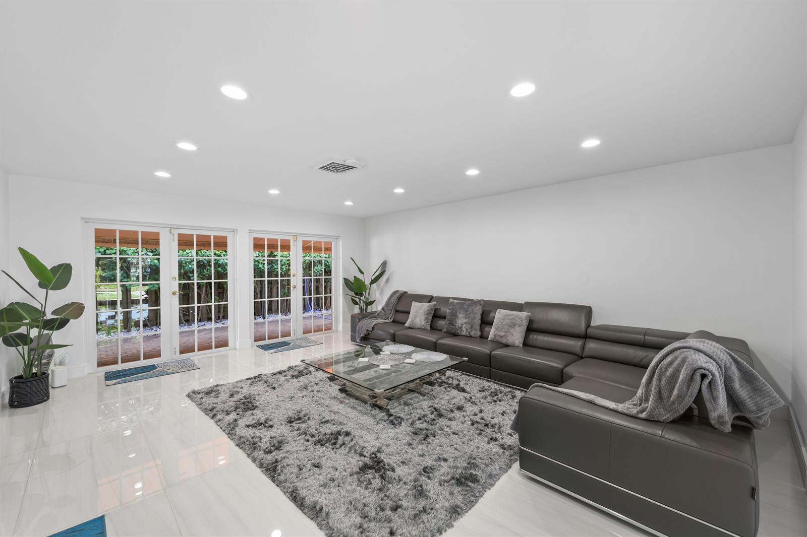A living room features white tile floors, a large gray sectional sofa, and glass doors — 3531 NE 30th Avenue, Lighthouse Point FL 33064, LIGHTHOUSE POINT, FL