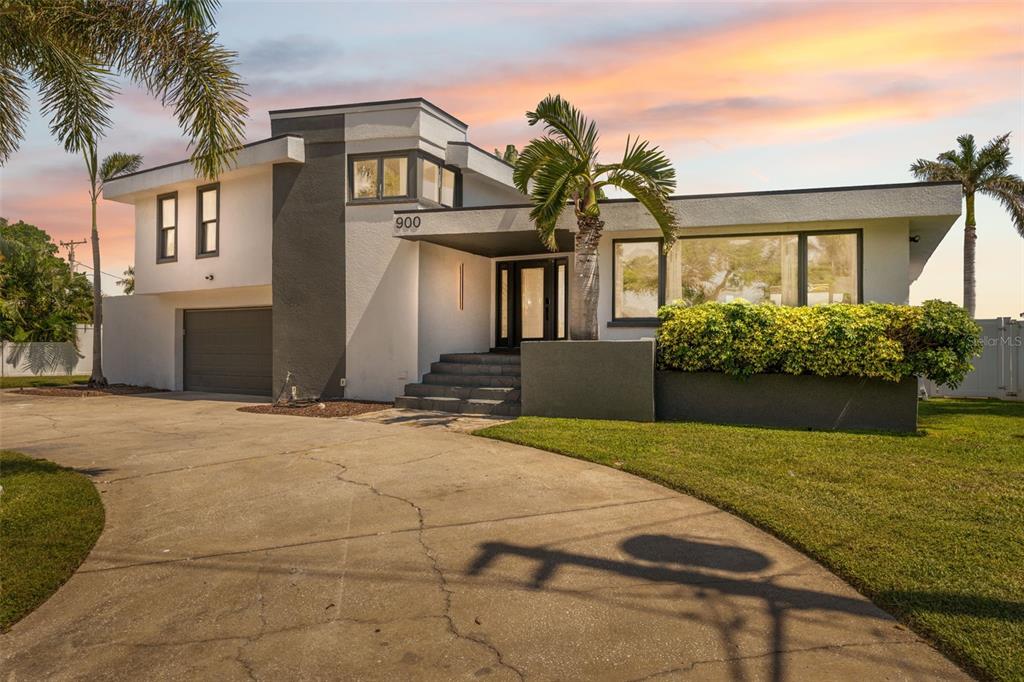 A two-story modern house with a concrete driveway, palm trees, and a gray garage door — 900 79TH STREET S, ST PETERSBURG, FL