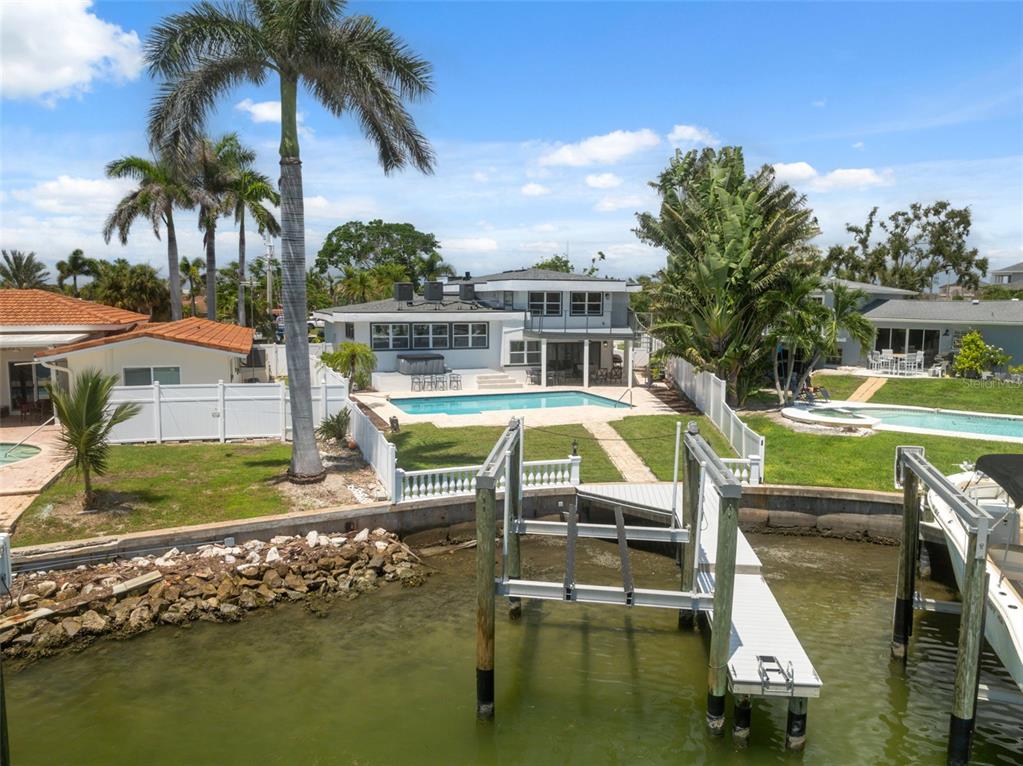 An aerial view of a waterfront house with a swimming pool, dock, and palm trees — 900 79TH STREET S, ST PETERSBURG, FL