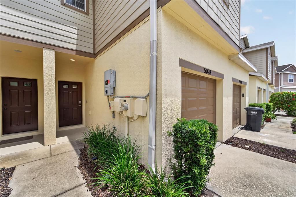 Exterior view of a multi-unit residential building with two brown doors and two garage doors — 5028 WHITE SANDERLING COURT, TAMPA, FL