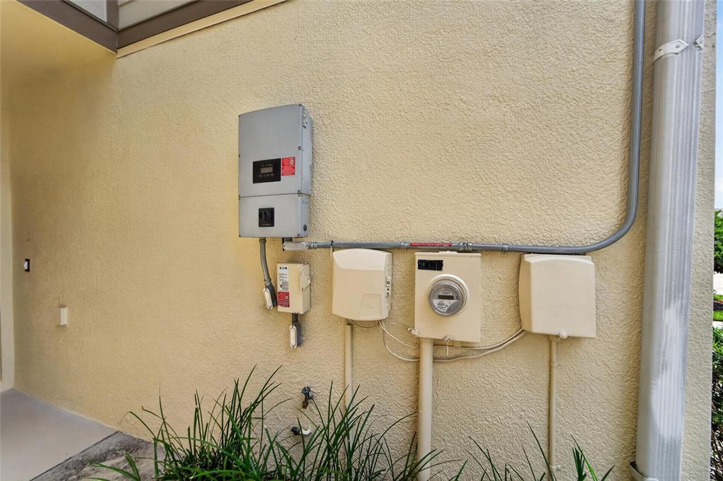 An exterior wall features a solar inverter, electrical meter, and various utility boxes — 5028 WHITE SANDERLING COURT, TAMPA, FL