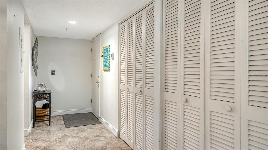 An entryway features tiled floors, a small side table, and several white louvered closet doors — 1001 BENJAMIN FRANKLIN DRIVE UNIT 110, SARASOTA, FL