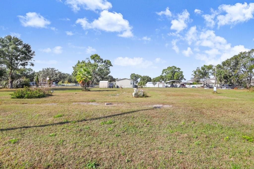 A large, grassy, open lot features scattered trees and a small shed in the distance — 4005 SW TIMBERWOOD DRIVE, LAKELAND, FL