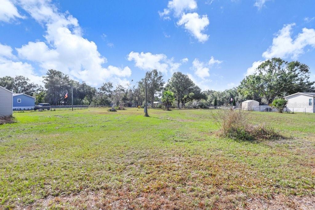 A large, grassy, open lot with scattered trees under a blue sky with clouds — 4005 SW TIMBERWOOD DRIVE, LAKELAND, FL