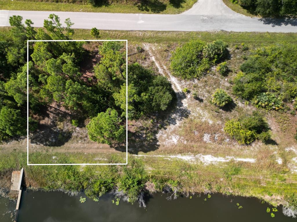 An aerial view shows a wooded lot bordering a road and a canal — 0 WYLAM DRIVE, NORTH PORT, FL