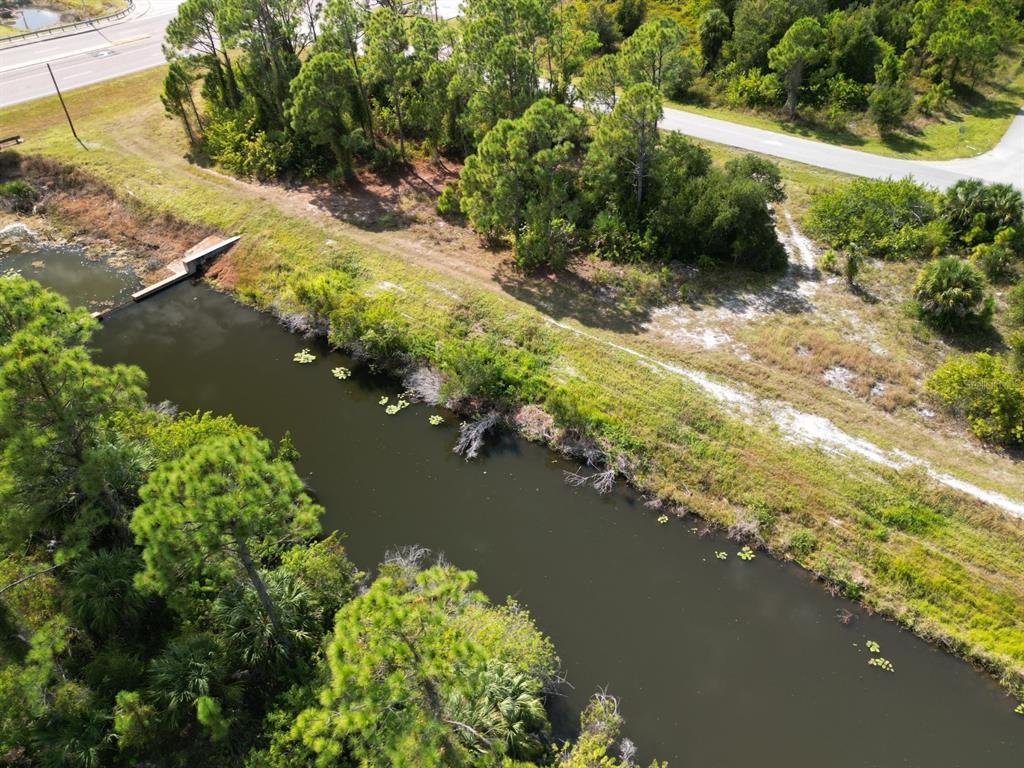 An aerial view shows a narrow canal bordered by trees and a dirt path — 0 WYLAM DRIVE, NORTH PORT, FL