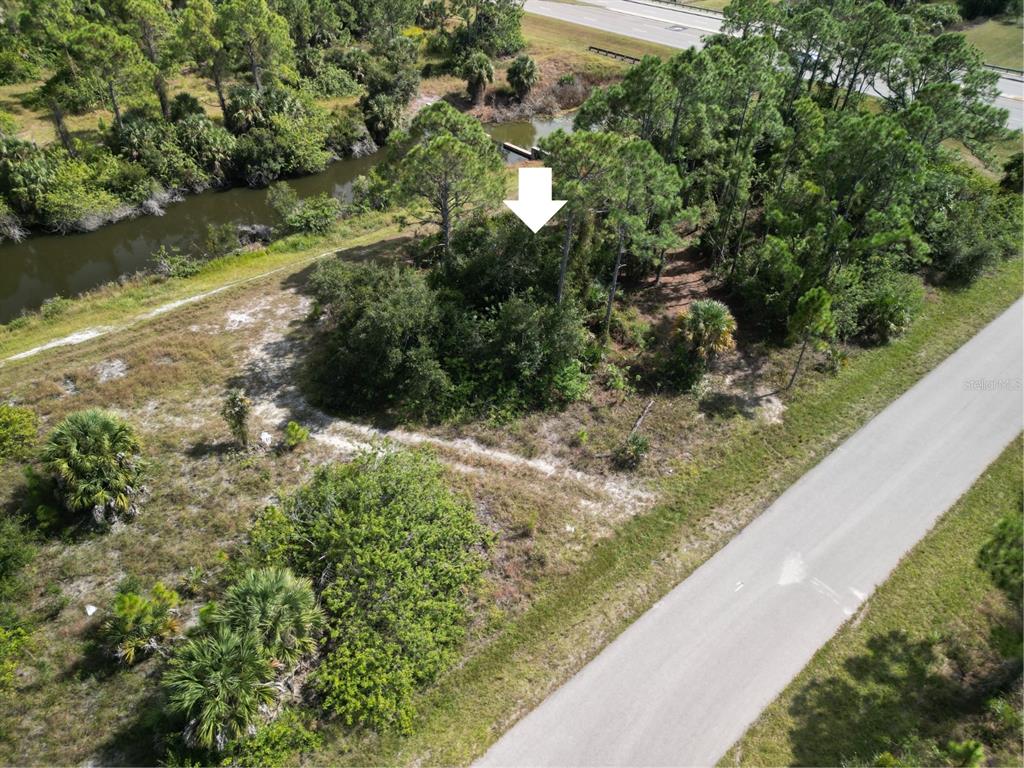 An aerial view shows a wooded, undeveloped lot bordered by a canal and a road — 0 WYLAM DRIVE, NORTH PORT, FL