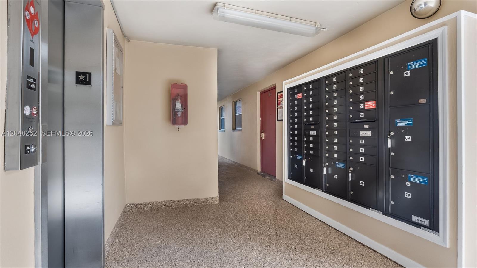 An indoor hallway features an elevator, a wall-mounted fire extinguisher, and a bank of mailboxes — 2851 E Sunrise Lakes Dr # 106, Sunrise FL 33322, SUNRISE, FL