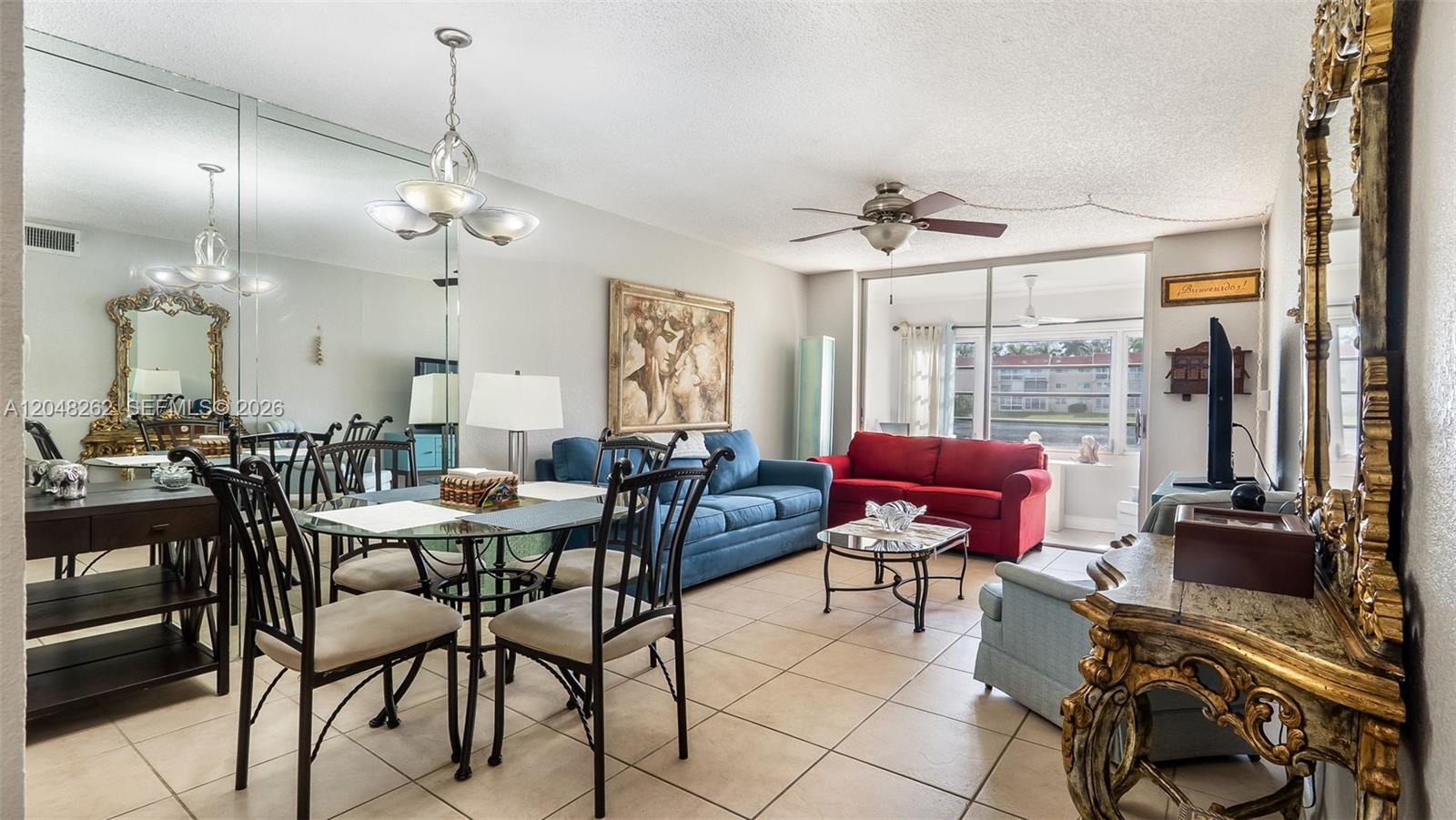A living and dining area features tiled floors, a mirrored wall, and two colorful sofas — 2851 E Sunrise Lakes Dr # 106, Sunrise FL 33322, SUNRISE, FL
