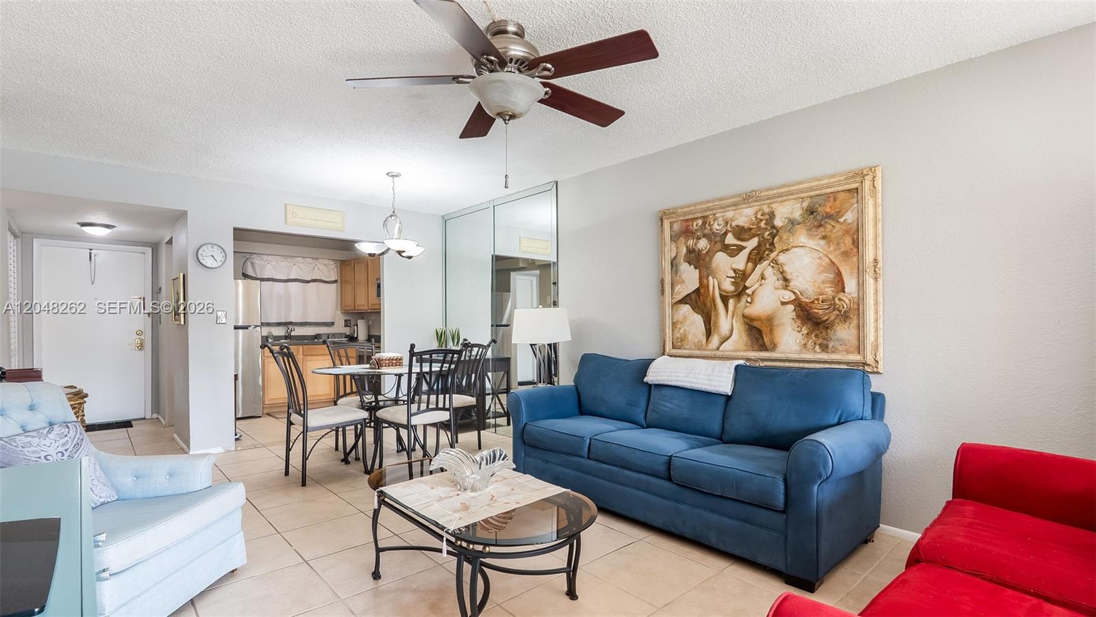A living room features a blue sofa, a red chair, and a dining area — 2851 E Sunrise Lakes Dr # 106, Sunrise FL 33322, SUNRISE, FL