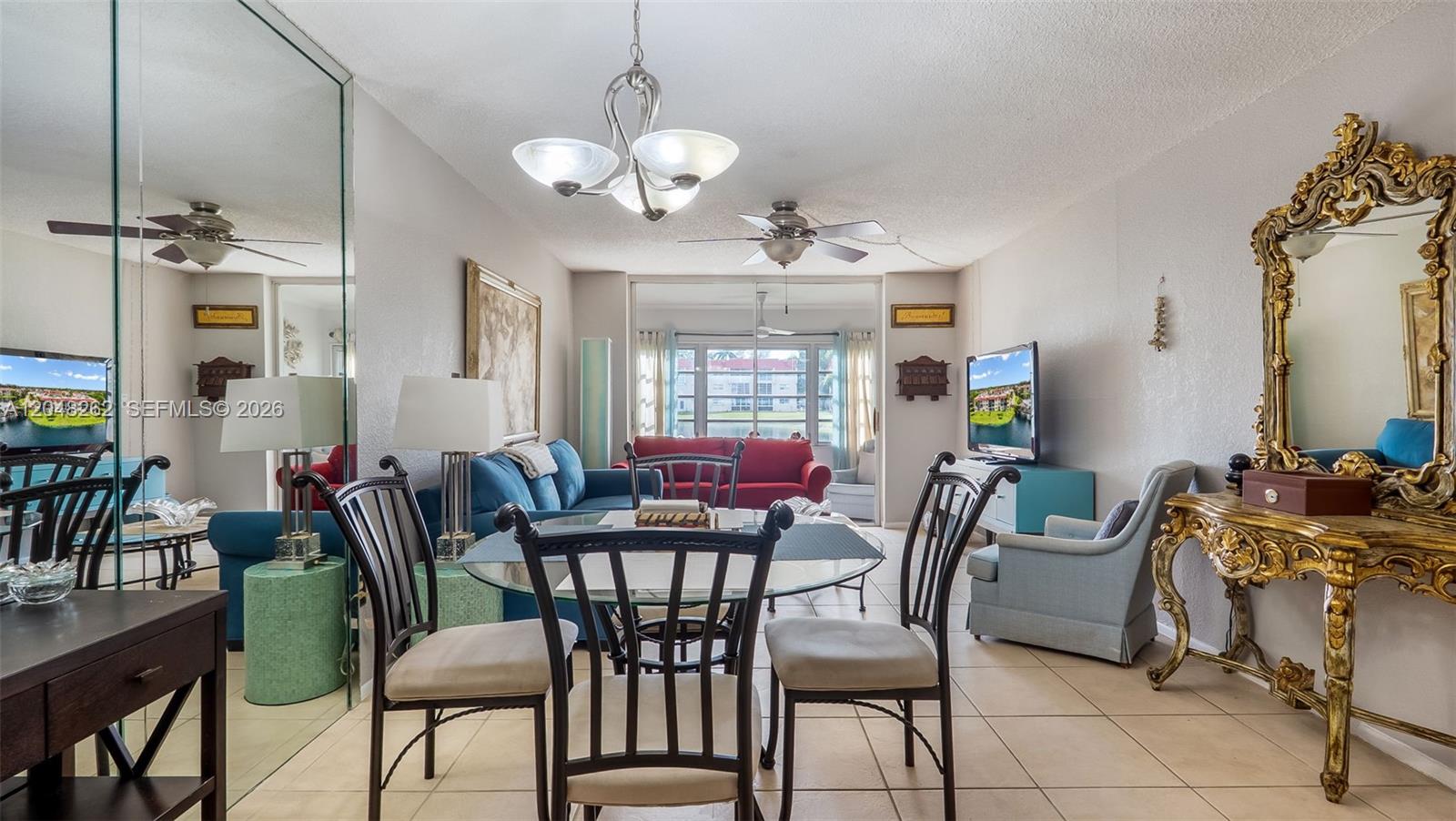 A living and dining area features a glass table, blue sofa, and ornate gold mirror — 2851 E Sunrise Lakes Dr # 106, Sunrise FL 33322, SUNRISE, FL