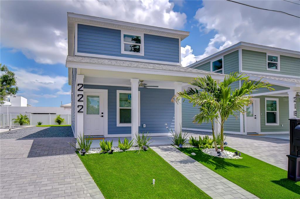 A blue two-story house features a covered front porch, a small lawn, and paved walkways — 222 8TH AVENUE DRIVE W, BRADENTON, FL