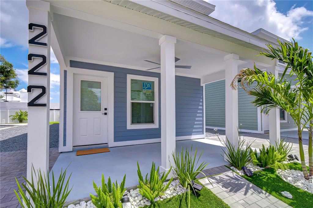 A blue-sided house features a covered front porch with white columns and a white door — 222 8TH AVENUE DRIVE W, BRADENTON, FL