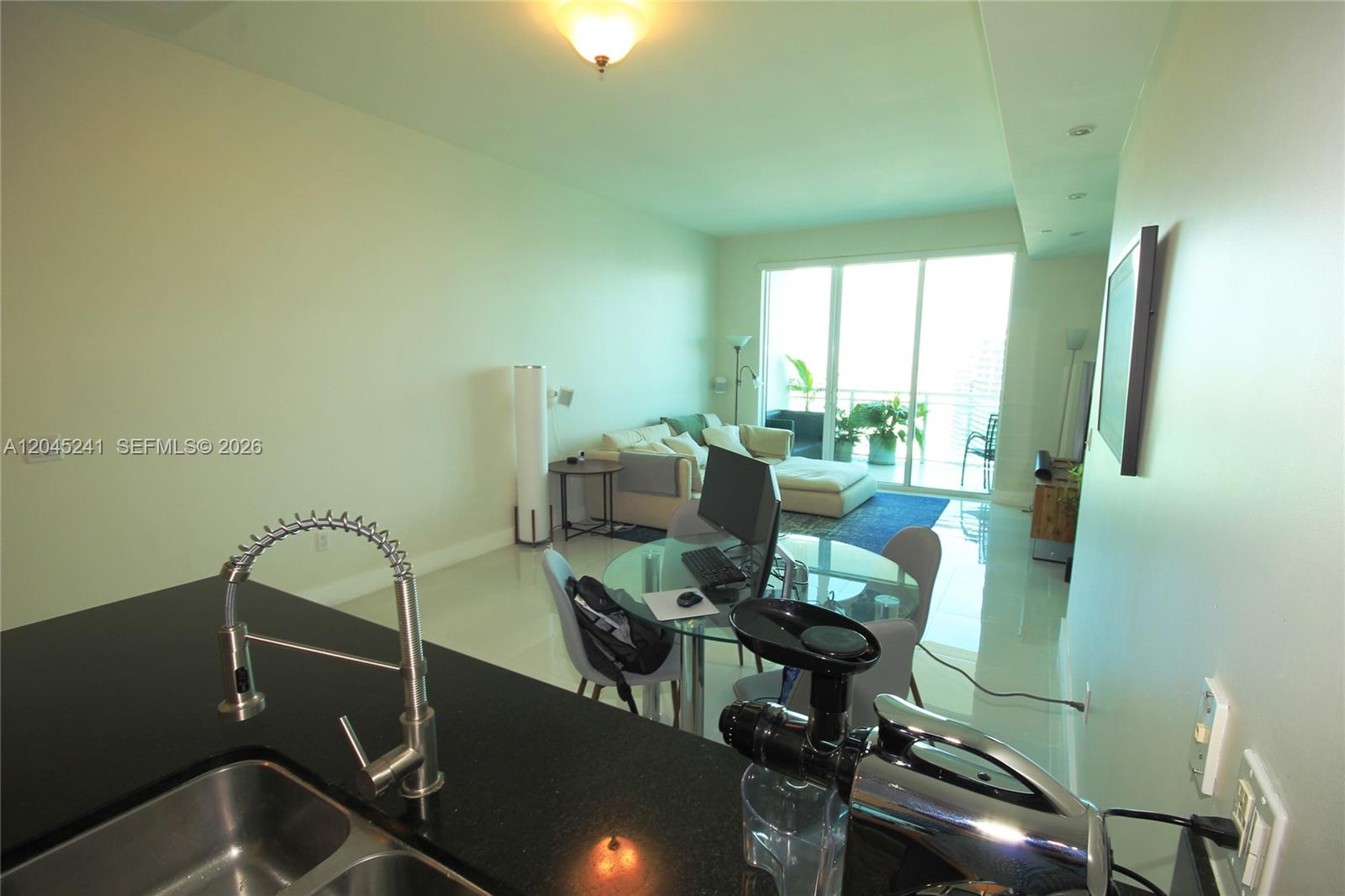 A kitchen island with a sink overlooks a living area with a glass dining table — 950 Brickell Bay Dr # 5000, Miami FL 33131, MIAMI, FL