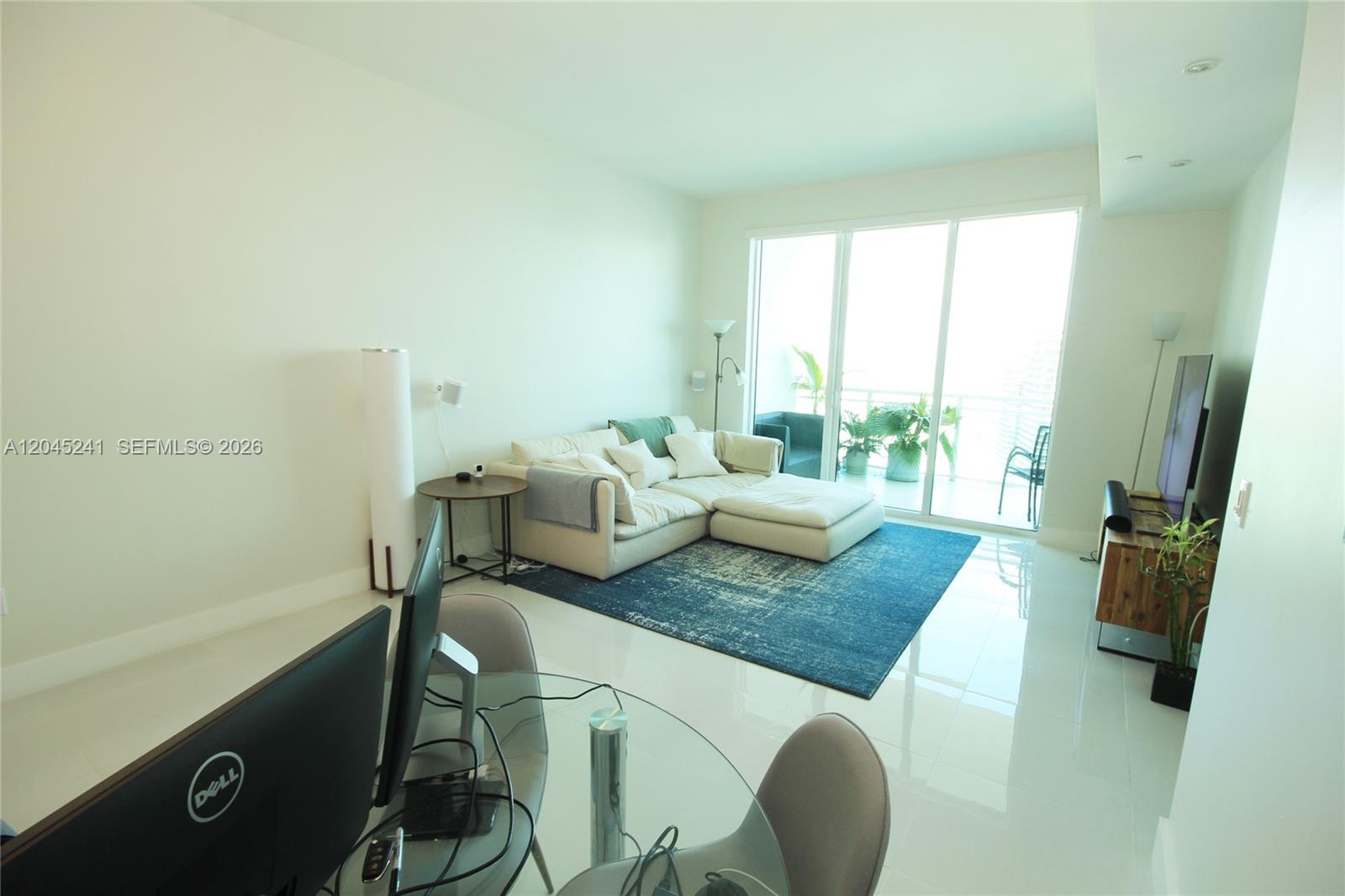 A living room features a white sectional sofa, a blue area rug, and a balcony — 950 Brickell Bay Dr # 5000, Miami FL 33131, MIAMI, FL