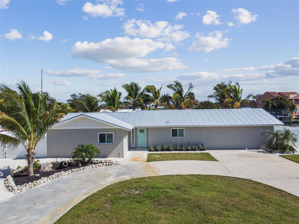 A single-story house with a light gray exterior, metal roof, and a teal front door — 4900 ARLINGTON ROAD, PALMETTO, FL