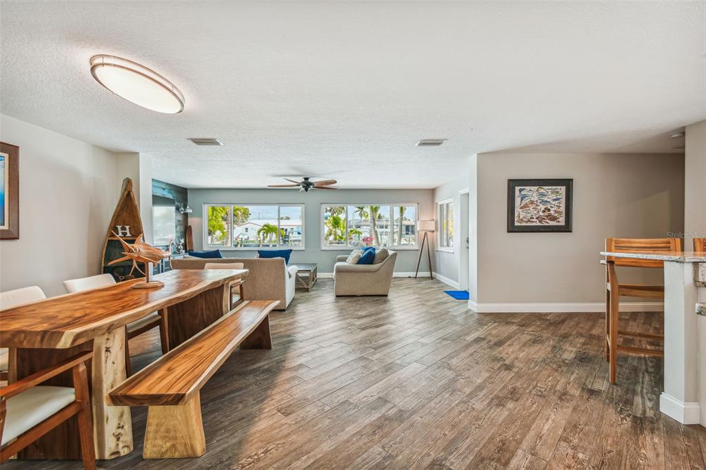 An open-concept living and dining area features wood-plank flooring, a live-edge table, and large windows — 4900 ARLINGTON ROAD, PALMETTO, FL