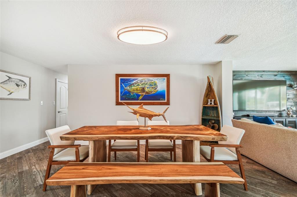 A dining room features a live-edge wood table, a matching bench, and nautical-themed wall art — 4900 ARLINGTON ROAD, PALMETTO, FL