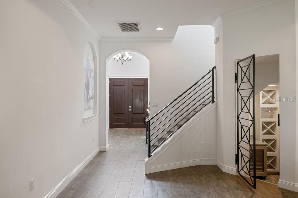 An entryway features wood-look tile flooring, a staircase with black railings, and a decorative door — 706 CANOPY ESTATES DRIVE, WINTER GARDEN, FL