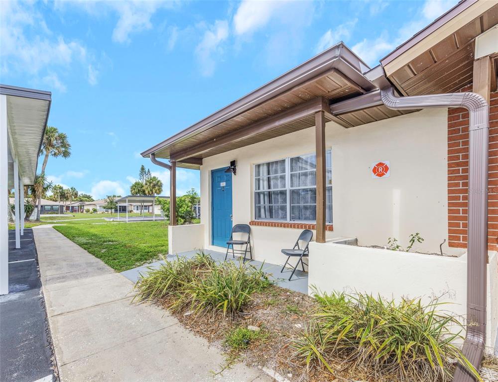 A single-story building exterior features a blue door, a small porch, and a brick accent wall — 24862 US HIGHWAY 19 N UNIT 2001, CLEARWATER, FL