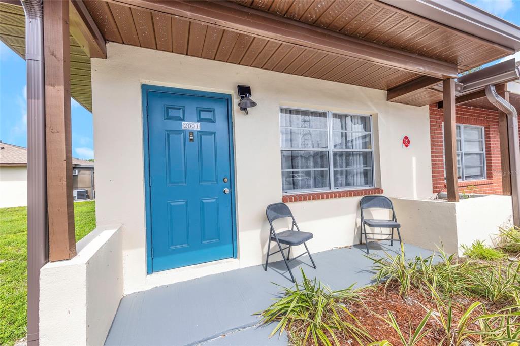 A blue front door with the number 2001 sits on a covered porch with two chairs — 24862 US HIGHWAY 19 N UNIT 2001, CLEARWATER, FL