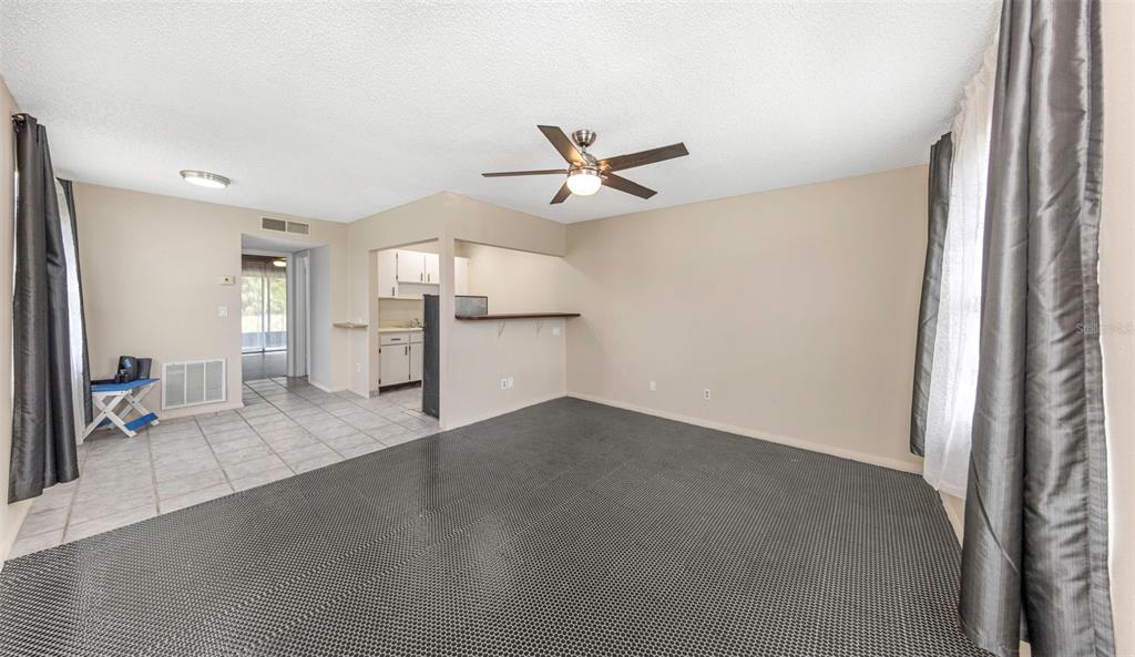 A living room with a ceiling fan, tiled entryway, and a breakfast bar to the kitchen — 24862 US HIGHWAY 19 N UNIT 2001, CLEARWATER, FL